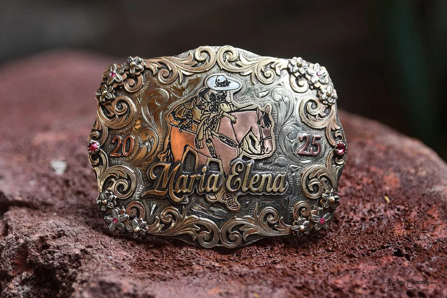 Hand-engraved Maria Elena trophy buckle with gold horse and flower overlays resting on red rock